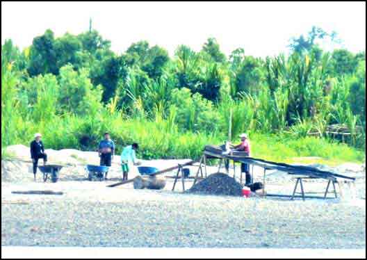 Men sift sediment by the river.